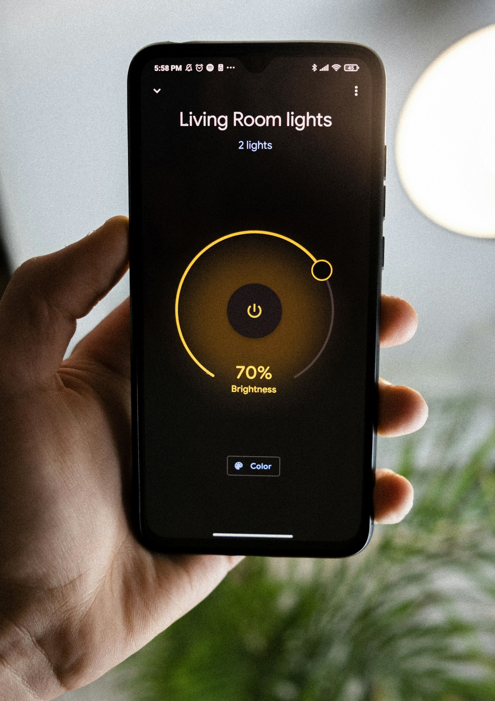 A hand adjusting the living-room lights from a phone